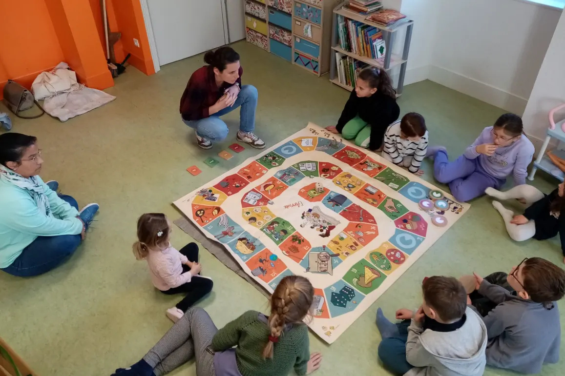 Animation Graines de Compost : des enfants assis en cercle autour d'un jeu de plateau sur le compostage