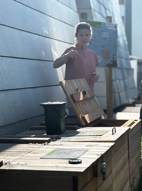 Une salariée dépose ses biodéchets dans un composteur en bois installé en entreprise