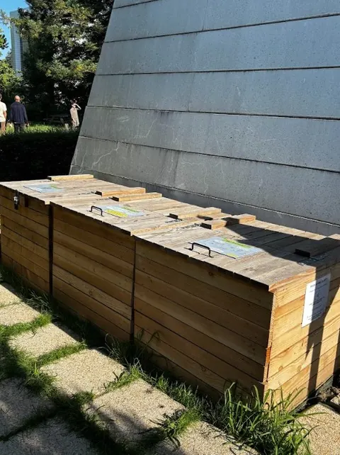 Composteurs en bois installés au pied d'un bâtiment d'entreprise