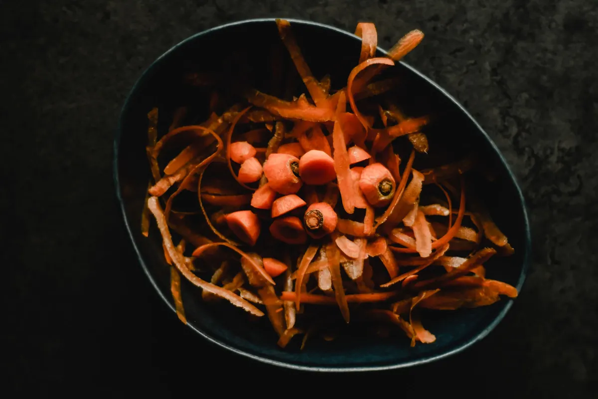 Épluchures de carottes dans un bol en cuisine, gros plan