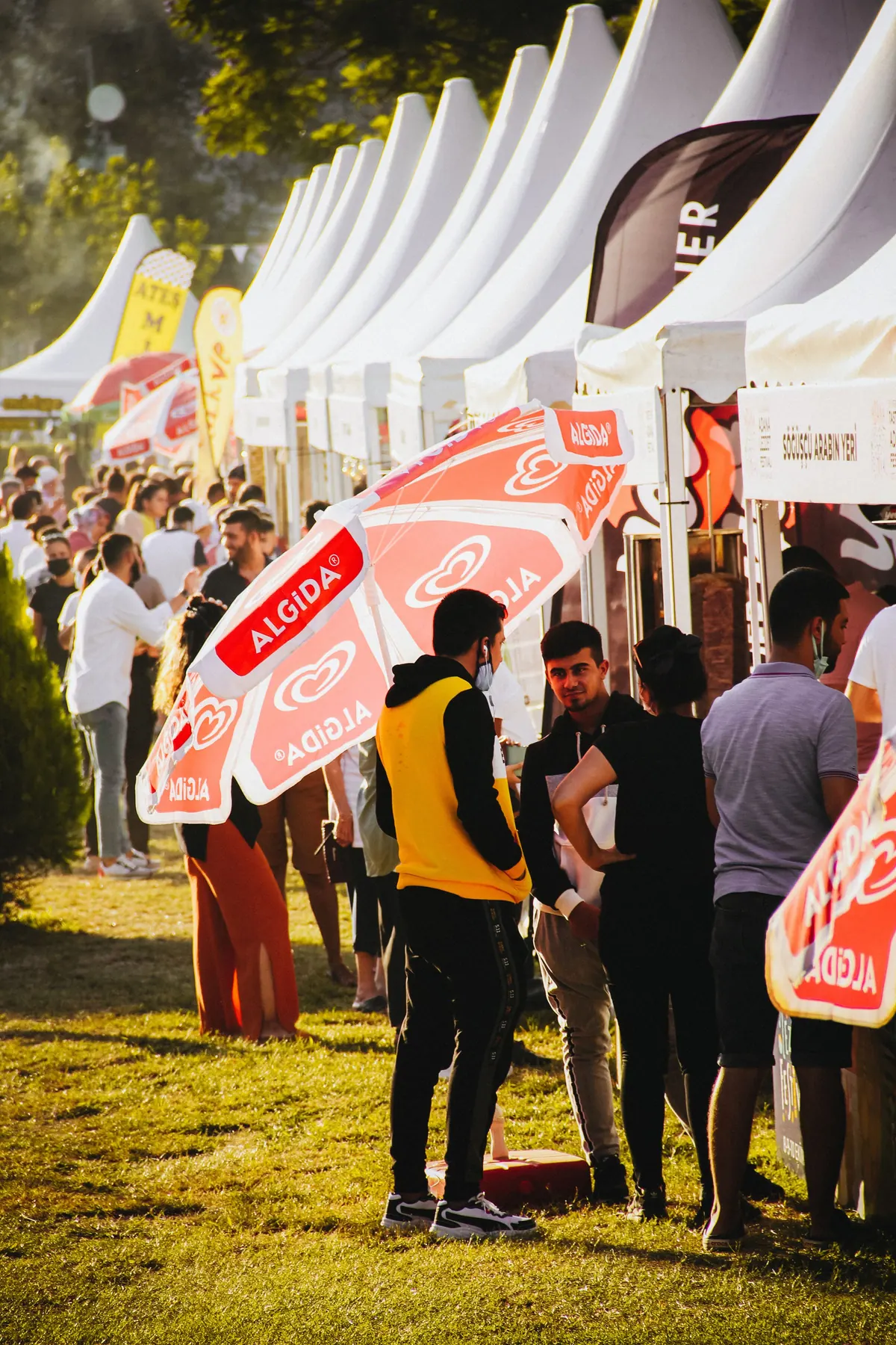 Public rassemblé devant des stands sous tentes lors d'un événement en plein air