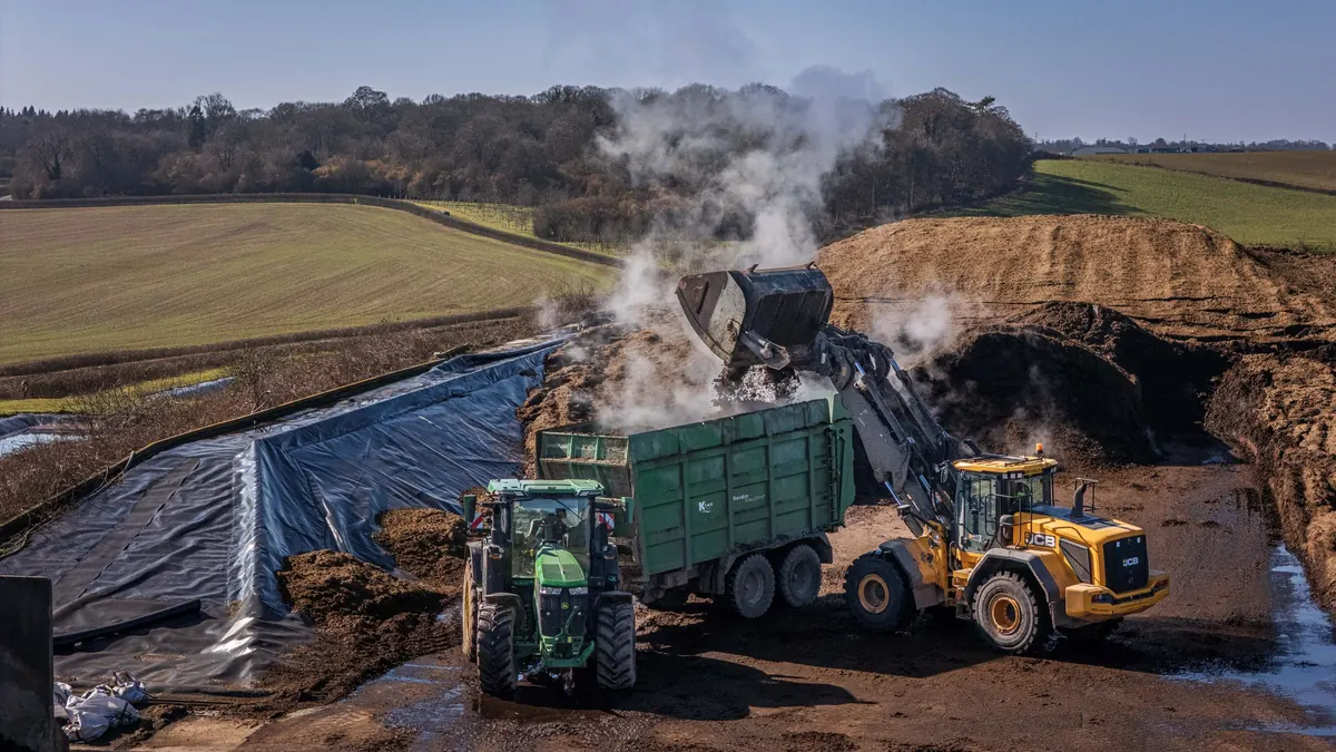 Plateforme de compostage industrielle : un chargeur retourne des andains de compost fumants